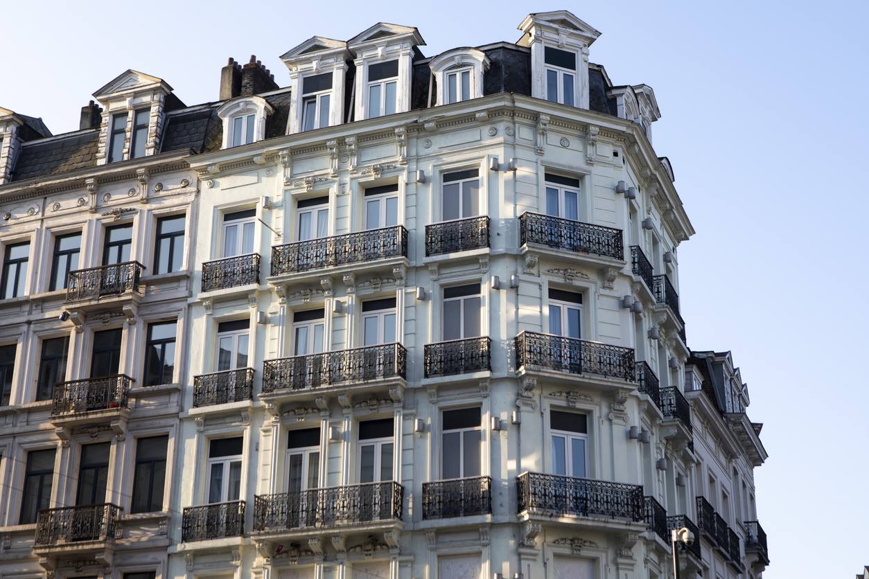 Immeuble de rapport bruxellois en pierre claire, cinq niveaux de balcons en fer forgé
